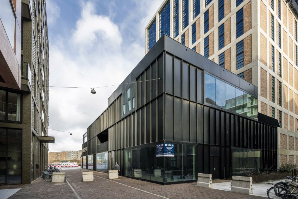 Modern zwart gebouw aan de Pieter Goosstraat met te huur-borden en omliggende hoogbouw.